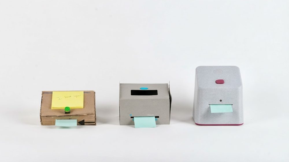 Three box-shaped prototypes, from cardboard to the final grey device